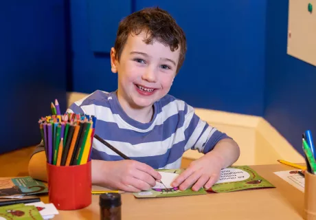 A boy drawing in a book with pencils